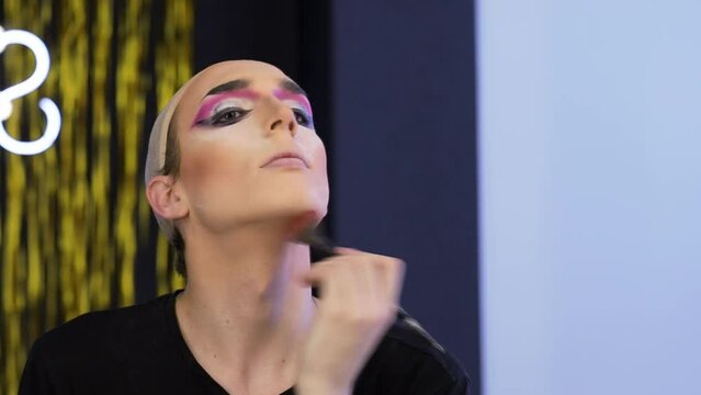 Young performer wearing hairnet applying makeup in front of mirror
