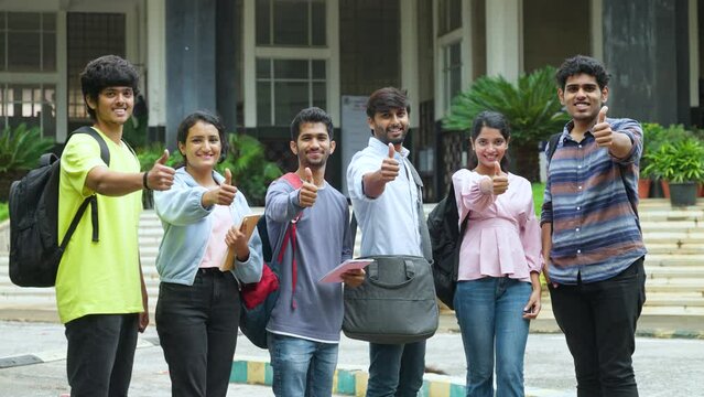 group of Confident students with backpack and books showing thumbs up by looking camera at college campus - concept of approval, successful education and skill development.