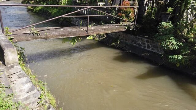 Establishing Shot Brown Dirty Water River, Rainy Season, Bali Indonesia Daylight Lonely Wooden Bridge