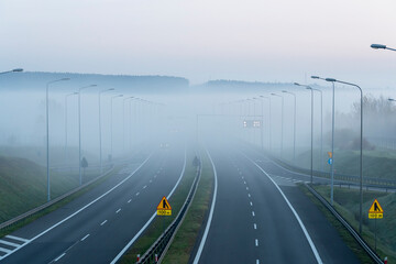 pusta niebieska mglista deszczowa autostrada z niską słabą widocznością w zimny wiosenny jesienny poranek. Sezonowa zła pogoda deszczowa ostrzeżenie o niebezpieczeństwie wypadku - obrazy, fototapety, plakaty