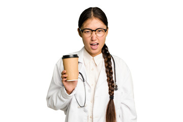 Young doctor asian woman holding a takeaway coffee isolated screaming very angry and aggressive.