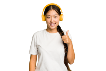 Young asian woman listening to music with headphones isolated smiling and raising thumb up