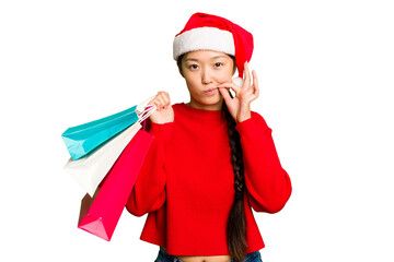 Young asian woman shopping a christmas presents isolated Young asian woman shopping a christmas presents isolated with fingers on lips keeping a secret.