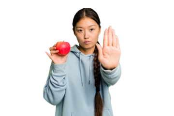 Young asian woman holding a red apple isolated standing with outstretched hand showing stop sign, preventing you.