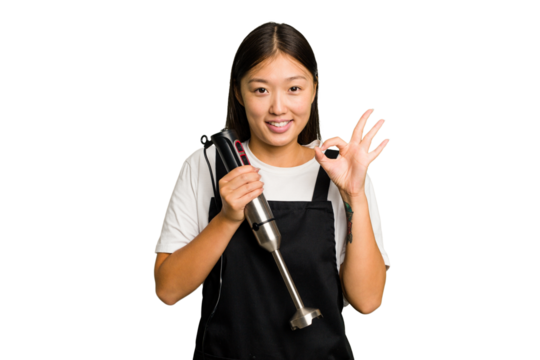 Young asian cook woman holding a blender isolated cheerful and confident showing ok gesture.