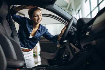 Fototapeta na wymiar Young woman choosing a car at car showroom