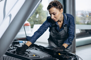 Young woman car mechanic checking car at car service