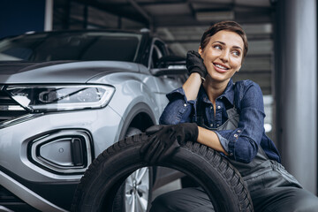 Fototapeta na wymiar Woman car mechanic changing tires at car service