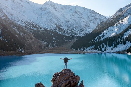 Feeling on top of the world man standing on a boulder over mountain lake