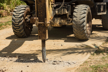 An excavator fitted with a hydraulic breaker destroying a portion of a damaged street. Road demolition in progress.