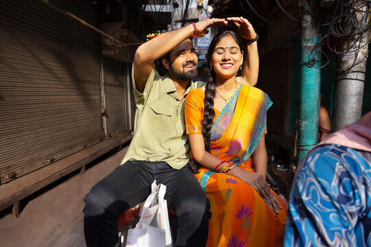 Husband Covering His Wife's Head From Sun Rays With His Hands While Riding Rickshaw 