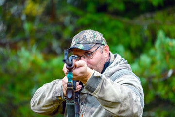 A man takes aim and shoots a combat carbine or guns in blurry focus at targets in a shooting range....