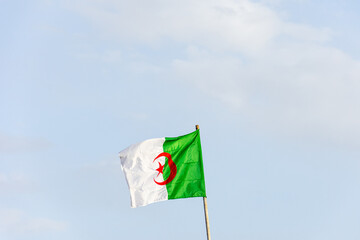 Algeria flag waving against a blue sky.