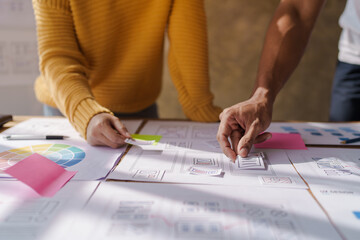 A UX design team is a confluence of user research, UX, UI design with layout paper on desk.