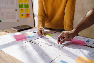 A UX design team is a confluence of user research, UX, UI design with layout paper on desk.