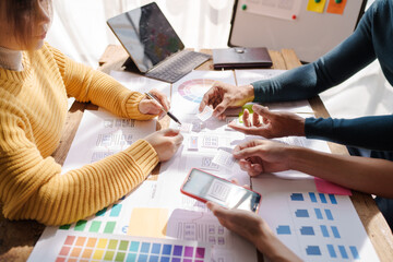 A UX design team is a confluence of user research, UX, UI design with layout paper on desk.