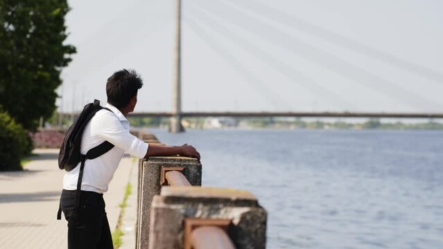 Student with white collar and backpack admires coastal city views