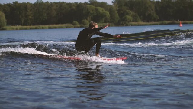 surfer on longboard surfing waves behind boat doing tricks