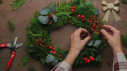 Hands making Christmas wreath using evergreen twigs. - Powered by Adobe