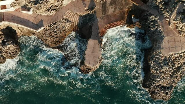 Ocean Waves Crashing On Rocky Coastline Of Citta del Mare-Perla Del Golfo In Summer In Terrasini, Palermo, Sicily, Italy. - aerial overhead
