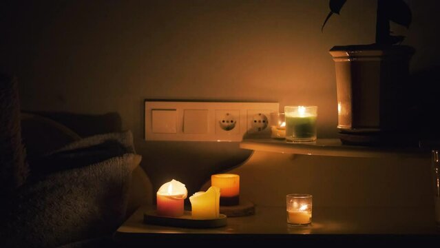 Candles in a dark room. Burning candles on the table and sockets on the background. No electricity in the house. Blackout in the city. Power outage, energy crisis concept