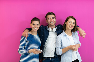 Group of young people in modern clothes posing and having fun isolated in front of pink background
