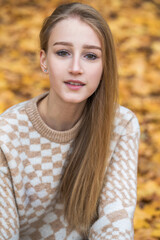 Portrait of a young beautiful blonde girl in an autumn park