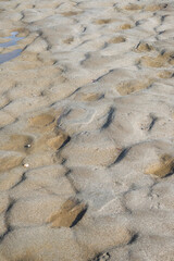 Fototapeta na wymiar Dry lagoon soil with wavy sand, granular forms and a bit of sea water