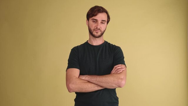 Happy brunet young man wearing t-shirt agrees with something in the yellow studio