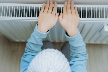 child warming hands over heater. Energy crisis in Europe