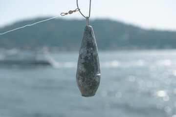 Fishing lead with blurred Bosphorus, angling concept banner, close-up fishing equipment, Angling in...