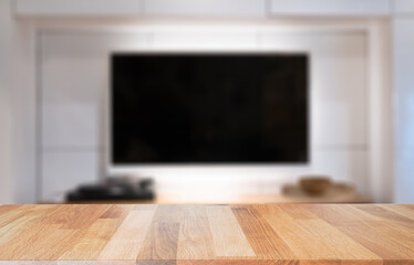 Empty wooden table top with tv in living room blurred background.