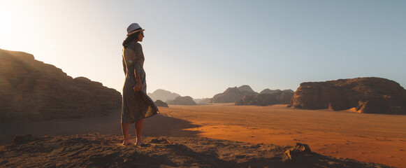 Woman tourist stand on cliff at viewpoint enjoy Wadi rum panorama on sunrise. Wadi Rum desert - valley Wadi Saabit. Jordan explore concept