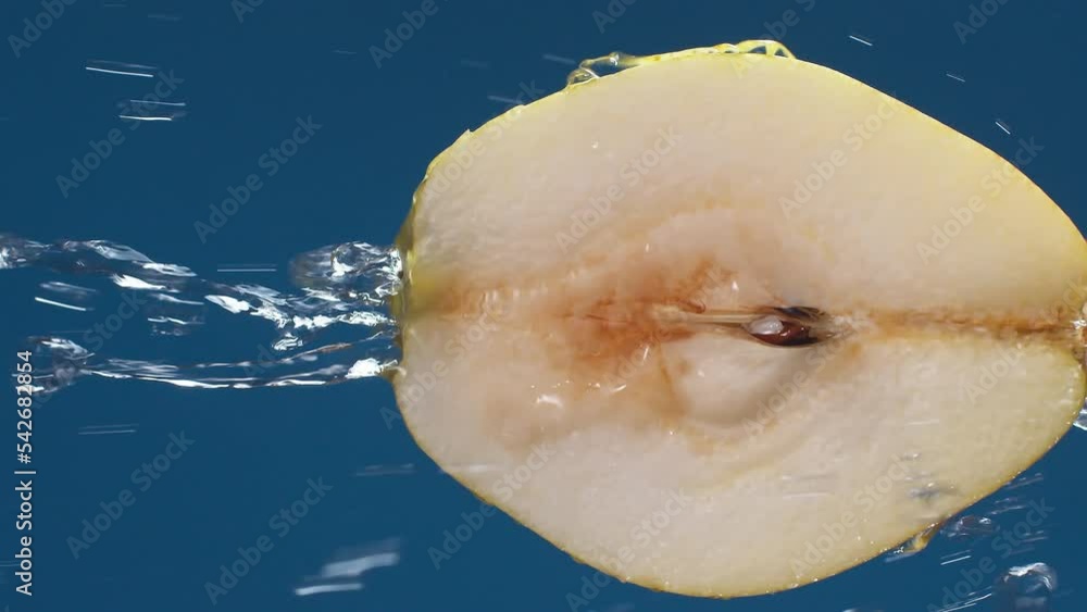 Poster vertical yellow half pear on a blue dark background with drops of water rolling down the pear and fl