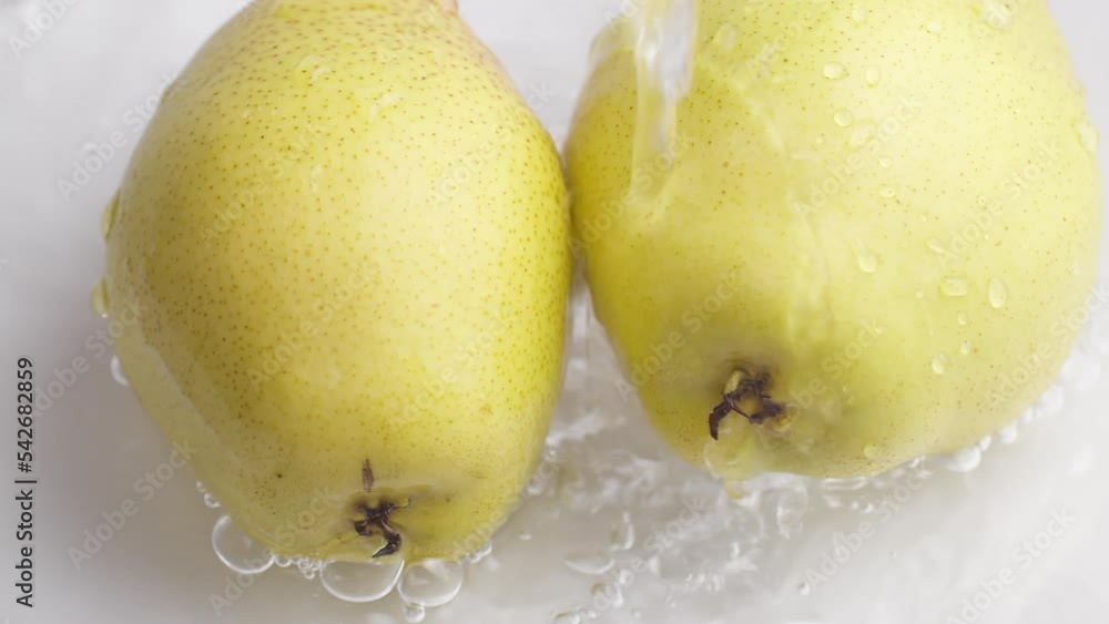 Poster yellow pear on a blue dark background with drops of water rolling down the pear and flowing splashin