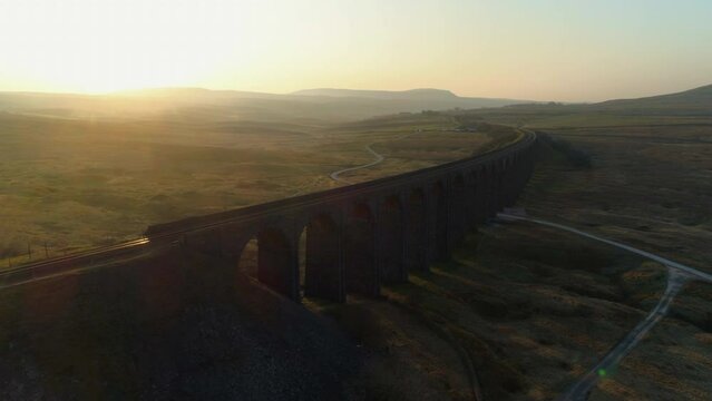 Aerial Drone Shot of Ribblehead Viaduct Train Bridge at Stunning Sunrise in Summer in Yorkshire Dales England UK with Hills in Background