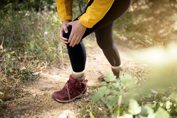 A woman is holding her knee joint in excruciating pain at uphill road.