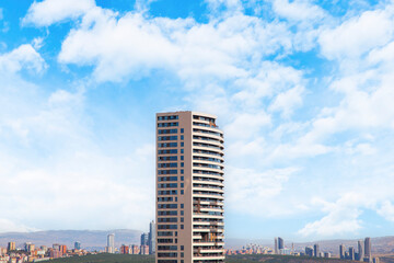 The lone skyscraper in the foreground of the city, the plaza. Blue sky. Business away from the city.