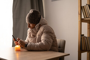Sick young man feel cold wearing at warm clothes watching movie on smartphone, annoyed guy shiver freezing warming at home wrapped with plaid, problem no central heating and flu