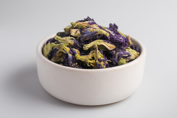 dried pea flowers in a white cup on a white background