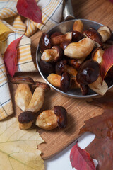 Several Imleria Badia or Boletus badius mushrooms commonly known as the bay bolete and vintage pan with mushrooms on wooden cutting board..