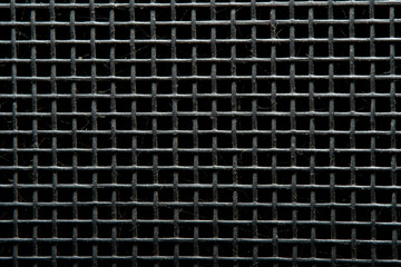 Close-up of an old black metal grill on a black background. Rods covered with dust.