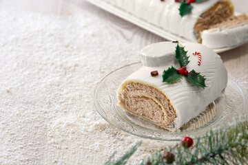 White chocolate yule log cake with ornaments on wooden table. Copy space