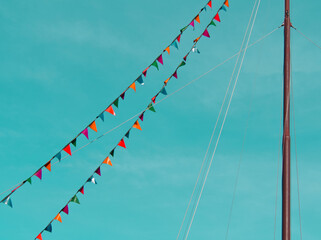 Boat mast draped in colorful flags and pennants on blue sky background. Triangle flag and bunting...