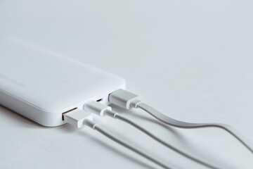Power bank, portative pocket charger with plugged cables on white background