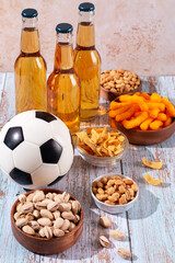 Beer in glasses and snack on wooden table with football ball, football game night food