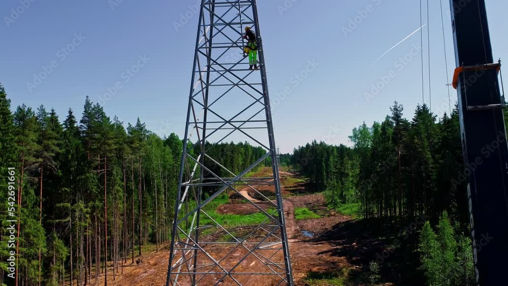 Poster aerial view of professional workers working on the installation of a high voltage tower in a forest 