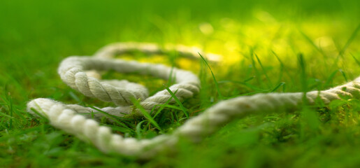 White sea rope on green grass. The paracord cord is a white hemp rope.