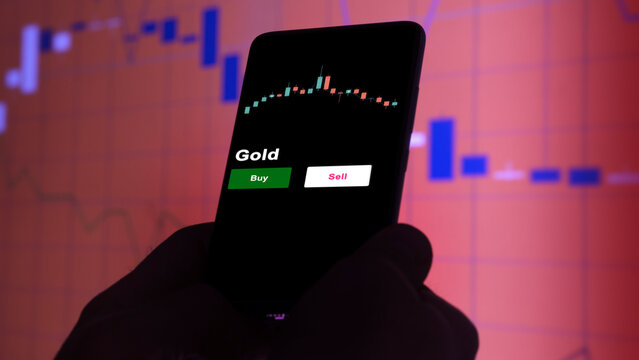 An investor's analyzing the Gold etf fund on screen. A phone shows the ETF's prices gold to invest