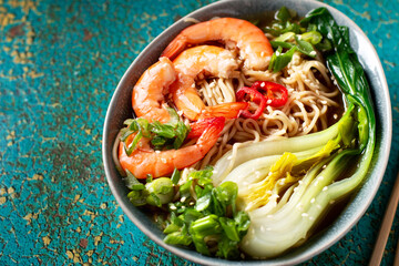 Ramen noodle soup with shrimp, green shallot, pak choi on green background